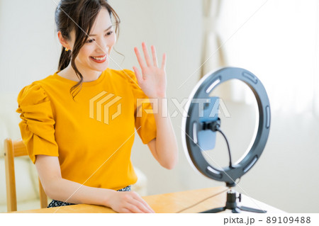 動画配信でフォロワーに手を振る20代女性 89109488