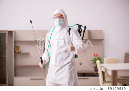 Young male contractor doing pest control at home 89109810