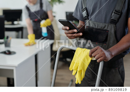 Hands of African American male cleaner choosing music in smartphone 89109819