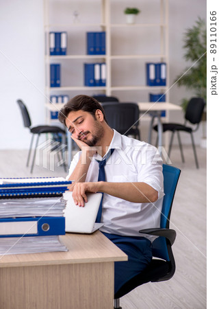 Young male employee unhappy with excessive work in the office 89110166