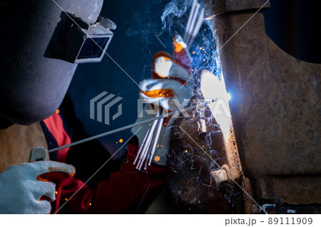 Welder in iron mask helmet welds with electric arc steel welding, Industrial worker at the factory welding steel structure, Welder is welding metalwork manufacturing and construction maintenance Welder in iron mask helmet welds with electric arc steel welding, Industrial worker at the factory welding steel structure, Welder is welding metalwork manufacturing and construction maintenance 89111909