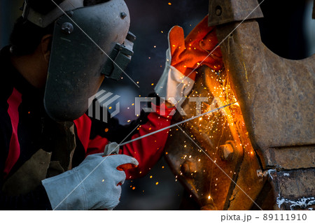 Welder in iron mask helmet welds with electric arc steel welding, Industrial worker at the factory welding steel structure, Welder is welding metalwork manufacturing and construction maintenance 89111910