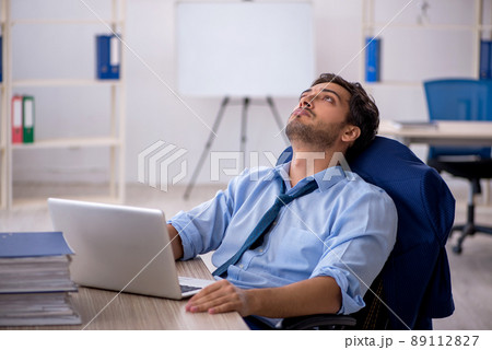 Young businessman employee and too much work in the office Young businessman employee and too much work in the office 89112827