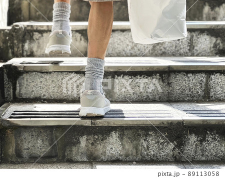 紙袋を持って階段を登る高齢女性の足元 89113058