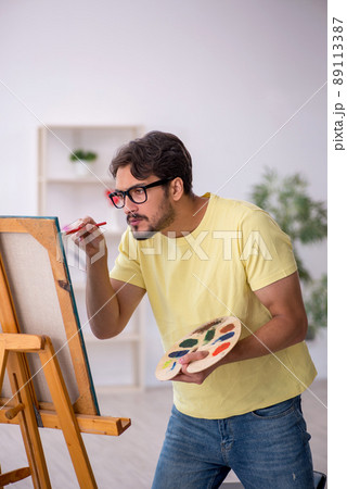 Young man enjoying painting at home 89113387
