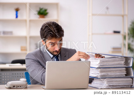 Young male employee and too much work in the office 89113412