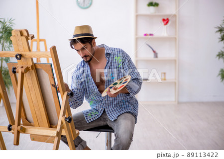 Young man enjoying painting at the studio 89113422