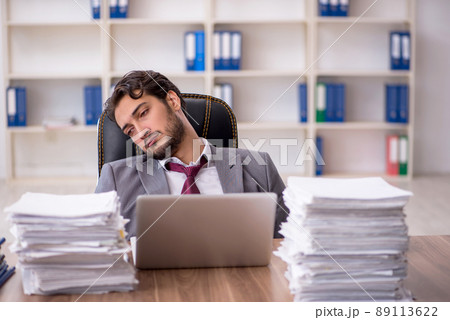 Young male employee and too much work in the office 89113622