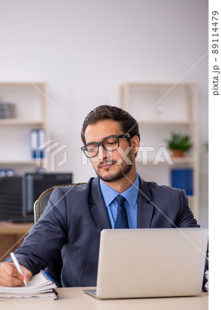 Young male employee and too much work in the office Young male employee and too much work in the office 89114479