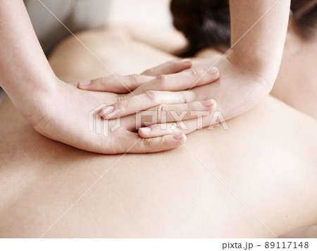 close-up of hands of a masseuse massaging back of a young asian woman close-up of hands of a masseuse massaging back of a young asian woman 89117148