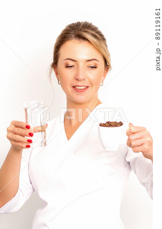 Coffee with water. The female nutritionist holds a cup of coffee beans and a glass of water in her hands on white background 89119161
