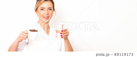 Coffee with water. The female nutritionist holds a cup of coffee beans and a glass of water in her hands on white background 89119173