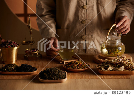 Front view of apocathery pouring tea into a glass with traditional medicine in wooden table  89122499