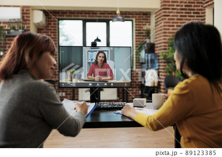Team of businesswomen working at job recruitment discussing curriculum vitae with remote applicant during online videocall meeting conference in startup company office. Teleconference call on screen 89123385