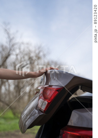 Person closes the trunk of the car. Side view of the vehicle. The concept of logistics, delivery and transportation Person closes the trunk of the car. Side view of the vehicle. The concept of logistics, delivery and transportation 89123420