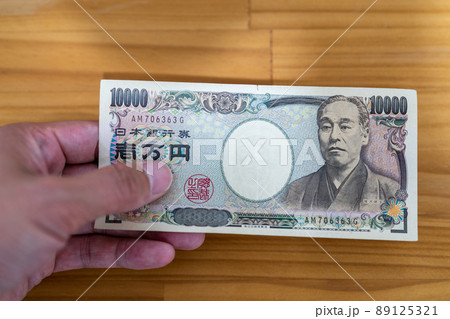 1万円札を手に持って渡す 89125321