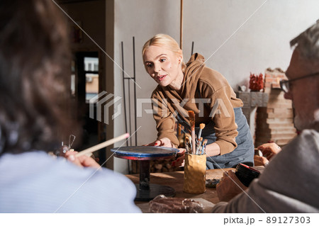 Female teacher explaining something to the mature people while they sitting at the master class 89127303