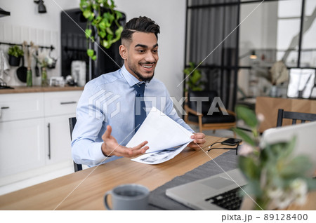 A dark-haired businessman having online meeting at his home office 89128400