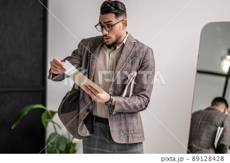 A young man in stylish jacket reading papers A young man in stylish jacket reading papers 89128428
