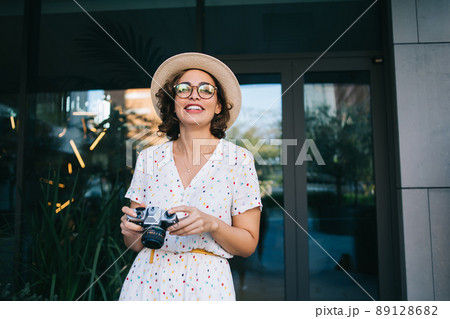 Happy female photographer near entrance of modern building Happy female photographer near entrance of modern building 89128682
