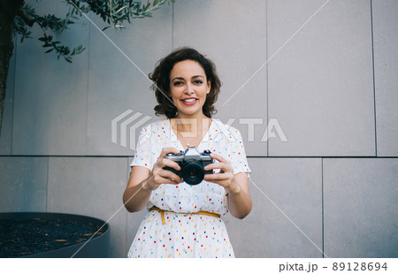 Smiling female with analog camera near wall 89128694