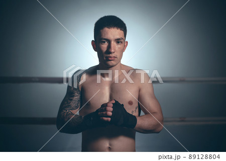 Boxer, man posing in bandage on boxing ring. Fitness and boxing concept. Boxer, man posing in bandage on boxing ring. Fitness and boxing concept. 89128804