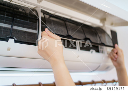 Asian woman cleaning a dirty and dusty air conditioning filter in her house. Housewife removing a dusty air conditioner filter. 89129175