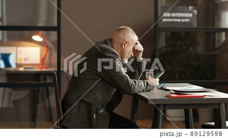 Mature man using his mobile phone at table while waiting for interviewer during job interview 89129598