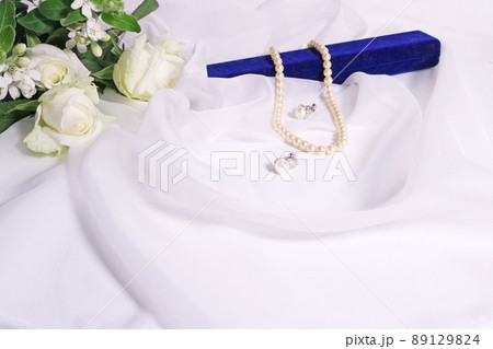 布の上の白いバラの花束と真珠のアクセサリーと青いアクセサリーケース 89129824