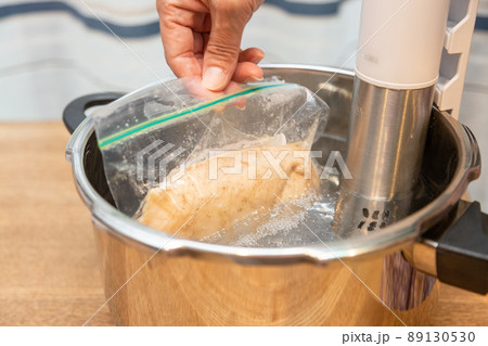 低温調理器で鶏ハムを作っている　鶏肉が入ったフリーザーバッグを見せる 89130530