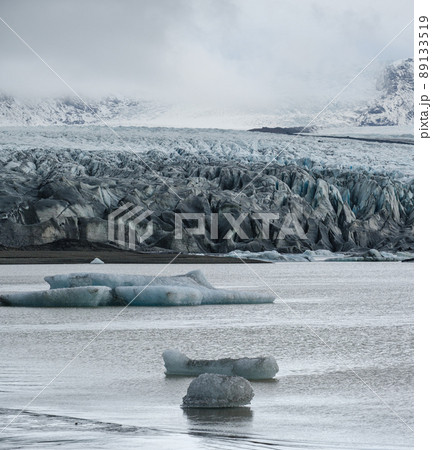 Skaftafellsjokull glacier, Iceland. Glacier tongue slides from the Vatnajokull icecap or Vatna Glacier near subglacial Esjufjoll volcano. Glacial lagoon with blocks of ice and surrounding mountains. Skaftafellsjokull glacier, Iceland. Glacier tongue slides from the Vatnajokull icecap or Vatna Glacier near subglacial Esjufjoll volcano. Glacial lagoon with blocks of ice and surrounding mountains. 89133519