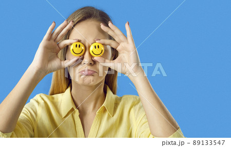 Sad woman trying to fake happiness, holding happy emojis and hiding her real emotions Sad woman trying to fake happiness, holding happy emojis and hiding her real emotions 89133547
