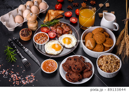 A delicious nutritious healthy breakfast with fried eggs, bacon, beans, a glass of juice, oat cookies, milk and jam A delicious nutritious healthy breakfast with fried eggs, bacon, beans, a glass of juice, oat cookies, milk and jam 89133644