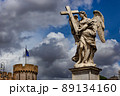 Marble statue of winged angel with a cross from the Ponte Sant'Angelo Bridge on the cloudy sky background. Rome, Italy. 89134160