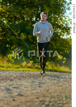 Man jogging in rural nature at beautiful summer day. Sport fitness model caucasian ethnicity training outdoor. Man jogging in rural nature at beautiful summer day. Sport fitness model caucasian ethnicity training outdoor. 89134417