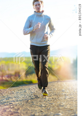 Man jogging in rural nature at beautiful summer day. Sport fitness model caucasian ethnicity training outdoor. Man jogging in rural nature at beautiful summer day. Sport fitness model caucasian ethnicity training outdoor. 89134419