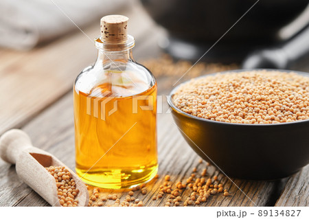 Bottle of natural organic mustard oil and bowl of whole grain mustard. 89134827