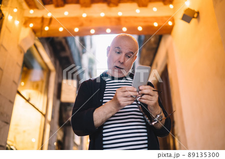 Amazed male blogger reading received email message with shock news about travel vacations, 89135300