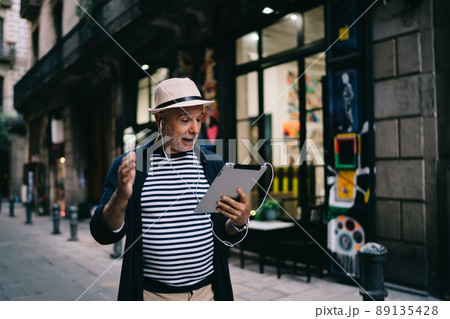 Aged man in straw hat using app on digital tablet for networking Aged man in straw hat using app on digital tablet for networking 89135428