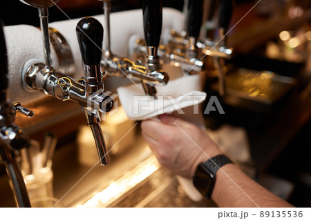 Waiter or bartender cleaning beer taps on the counter in pub and restaurant. 89135536