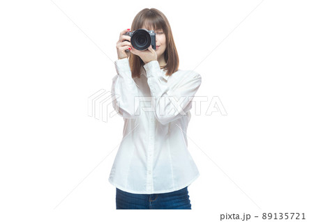Portrait of a young woman in a white shirt taking pictures with a camera. The concept of a successful photographer, wedding photographer, photo for documents. Isolated on white background. Portrait of a young woman in a white shirt taking pictures with a camera. The concept of a successful photographer, wedding photographer, photo for documents. Isolated on white background. 89135721