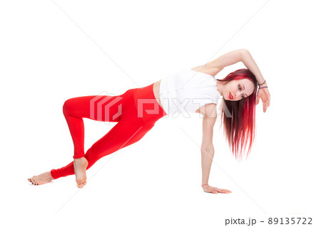 A beautiful, athletic, slim, smiling and cheerful woman in a white top and red sweatpants performs stretching and Pilates elements. Lifestyle concept with sports and gym, healthy lifestyle. Isolated A beautiful, athletic, slim, smiling and cheerful woman in a white top and red sweatpants performs stretching and Pilates elements. Lifestyle concept with sports and gym, healthy lifestyle. Isolated 89135722