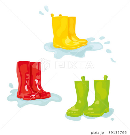 Set of colorful rubber boots in puddle of water