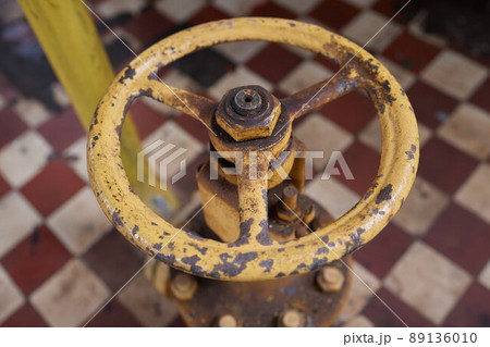 Close-up at pipeline valve which is using to control production process in the oil refinery plant. Selective focus at the valve handle wheel, Heavy industrial object photo. 89136010