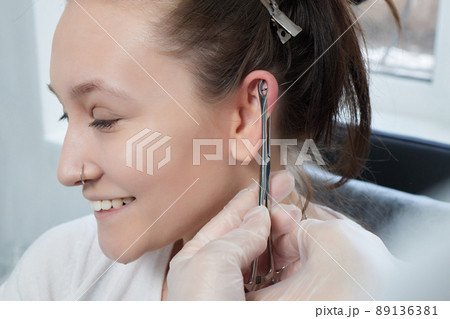 piercings on an ear. Conch and helix piercings close up. Professional holding the jewel. piercings on an ear. Conch and helix piercings close up. Professional holding the jewel. 89136381
