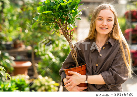 Portrait of a pretty girl florist with a flowerpot in her hands at the garden center Portrait of a pretty girl florist with a flowerpot in her hands at the garden center 89136430