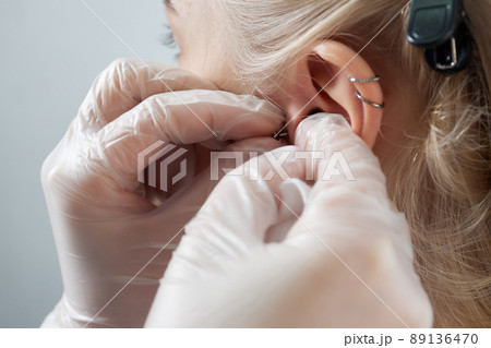 Professional holding the jewel of piercing day just before screw the ball. Tragus type. Professional holding the jewel of piercing day just before screw the ball. Tragus type. 89136470