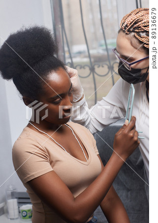 Close up of woman's ear with pierced on her ear for treatment of the pain some place on her body by Chinese doctor. Close up of woman's ear with pierced on her ear for treatment of the pain some place on her body by Chinese doctor. 89136679