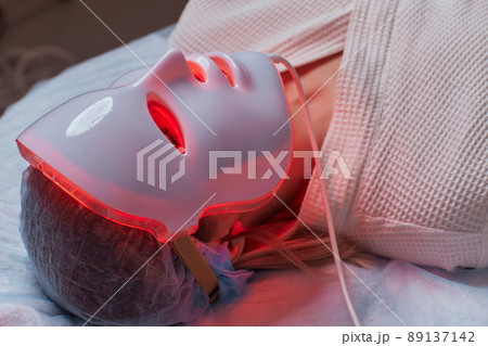LED light anti-aging mask for facial skin care in a spa slow motion. A woman lies on a couch in a special mask. Modern technologies of beauty and health. LED light anti-aging mask for facial skin care in a spa slow motion. A woman lies on a couch in a special mask. Modern technologies of beauty and health. 89137142