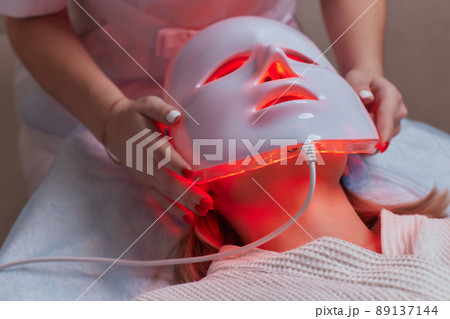 LED light anti-aging mask for facial skin care in a spa slow motion. A woman lies on a couch in a special mask. Modern technologies of beauty and health. LED light anti-aging mask for facial skin care in a spa slow motion. A woman lies on a couch in a special mask. Modern technologies of beauty and health. 89137144